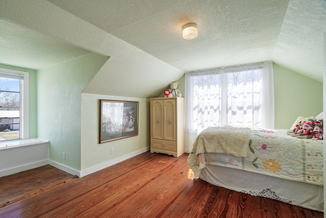 bedroom with multiple windows, a textured ceiling, and wood finished floors