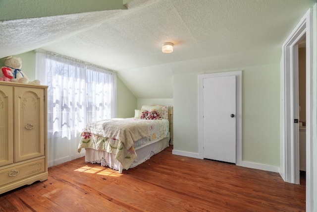 bedroom featuring light wood-style flooring, a textured ceiling, and lofted ceiling