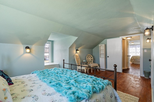 bedroom with a textured ceiling, lofted ceiling, and wood finished floors