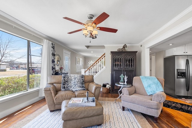 living area with crown molding, baseboards, ceiling fan, stairway, and wood finished floors