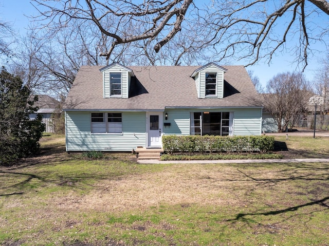 new england style home with a front yard and a shingled roof