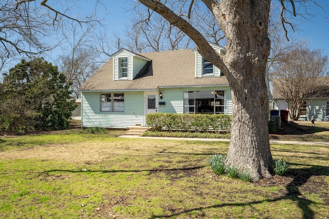 new england style home featuring a front lawn and a shingled roof