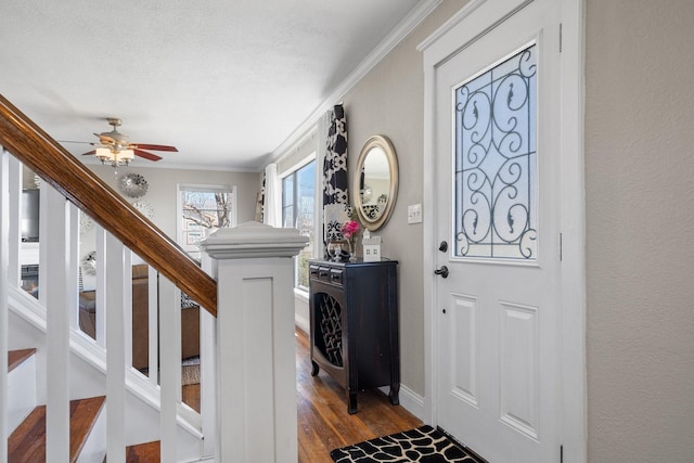 foyer with stairway, a ceiling fan, baseboards, dark wood finished floors, and crown molding