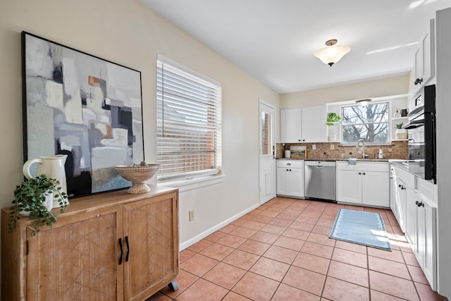 kitchen featuring tasteful backsplash, oven, light tile patterned flooring, white cabinets, and stainless steel dishwasher