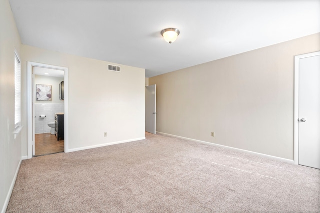 unfurnished bedroom featuring visible vents, baseboards, carpet, and ensuite bathroom