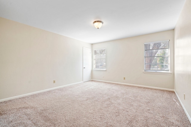 unfurnished room featuring light carpet, plenty of natural light, and baseboards