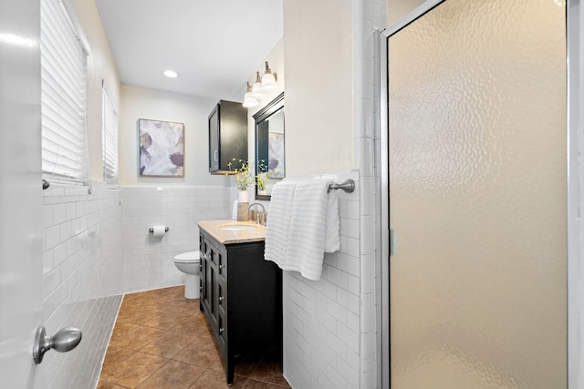 full bathroom featuring vanity, a stall shower, tile patterned floors, toilet, and tile walls