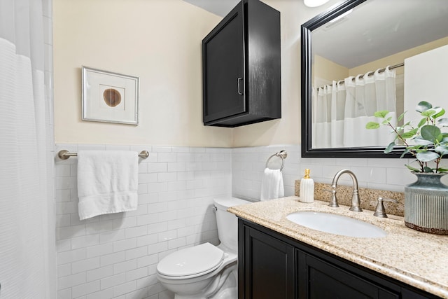 full bathroom with visible vents, toilet, vanity, wainscoting, and tile walls