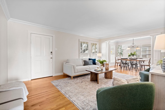 living area featuring plenty of natural light, light wood-style floors, baseboards, and ornamental molding