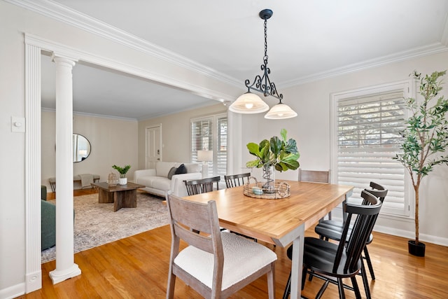 dining room featuring crown molding, light wood-style floors, and decorative columns