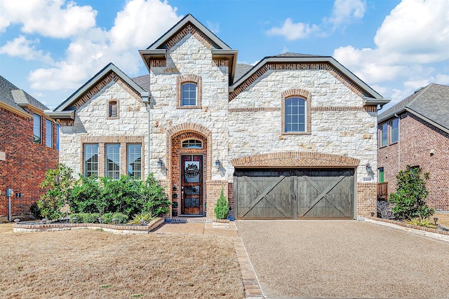 french provincial home featuring stone siding, driveway, and a garage