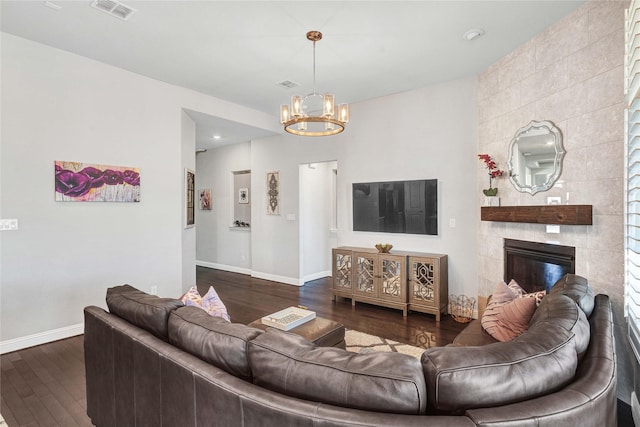 living room featuring dark wood-style floors, visible vents, baseboards, and a notable chandelier