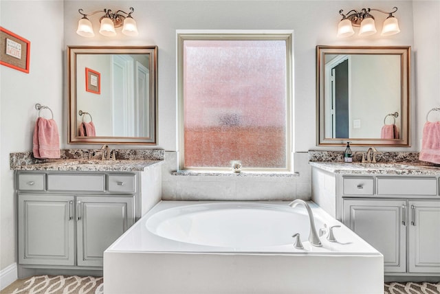 full bath featuring a sink, a garden tub, and two vanities