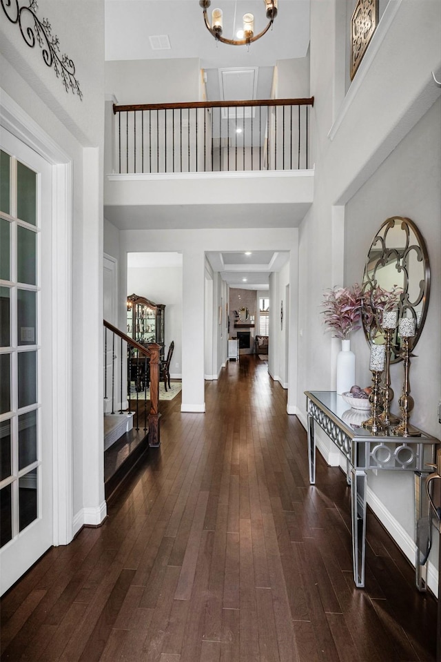 entrance foyer featuring baseboards, stairway, a towering ceiling, hardwood / wood-style flooring, and a notable chandelier