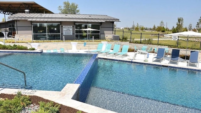 community pool with a patio area, central AC, and fence