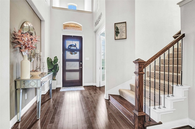 foyer with dark wood finished floors, baseboards, stairs, and a high ceiling