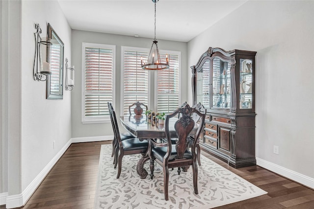 dining room featuring a notable chandelier, dark wood-style floors, and baseboards