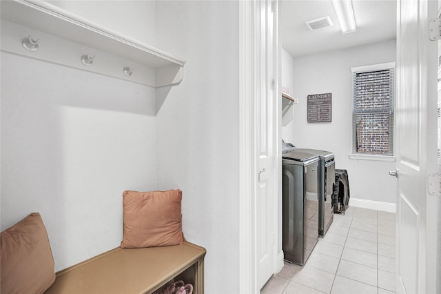 laundry area with visible vents, independent washer and dryer, light tile patterned floors, baseboards, and laundry area