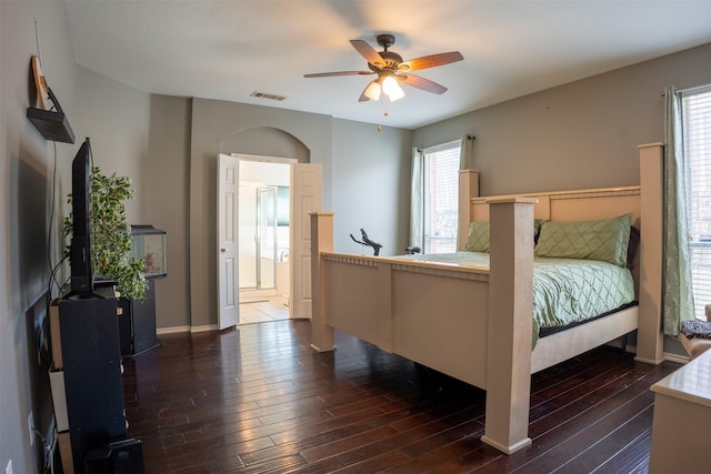 bedroom featuring ceiling fan, visible vents, dark wood-style flooring, and connected bathroom