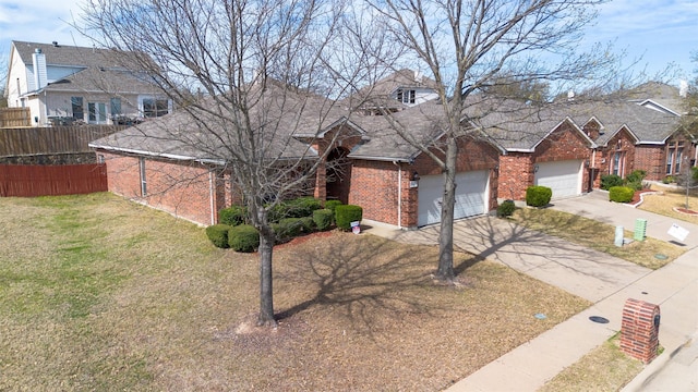 view of front of property with a front yard, fence, driveway, an attached garage, and brick siding