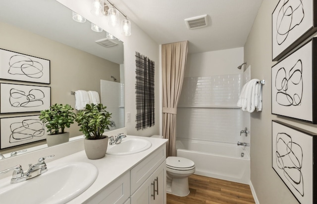 bathroom with toilet, wood finished floors, visible vents, and a sink