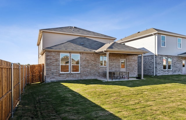 rear view of house with a patio, a lawn, brick siding, and a fenced backyard