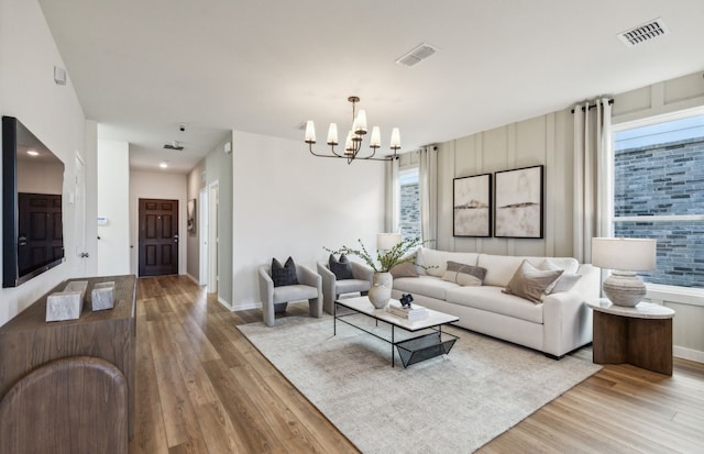 living area with a wealth of natural light, visible vents, and a notable chandelier