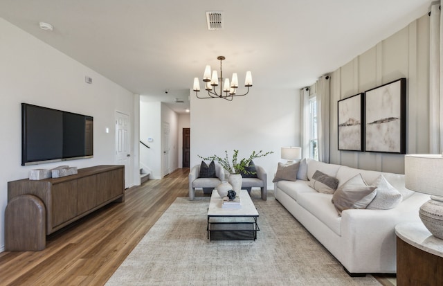 living room with visible vents, light wood-style floors, an inviting chandelier, and stairs