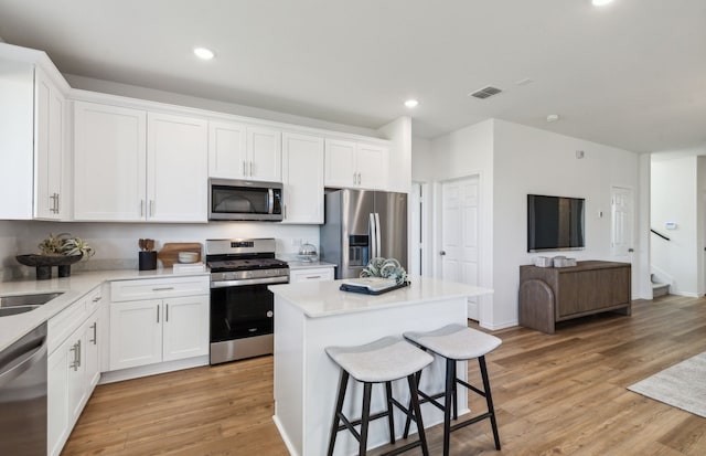 kitchen with a breakfast bar, white cabinetry, visible vents, and appliances with stainless steel finishes