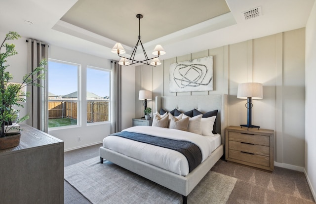 bedroom with a chandelier, visible vents, a tray ceiling, and carpet floors