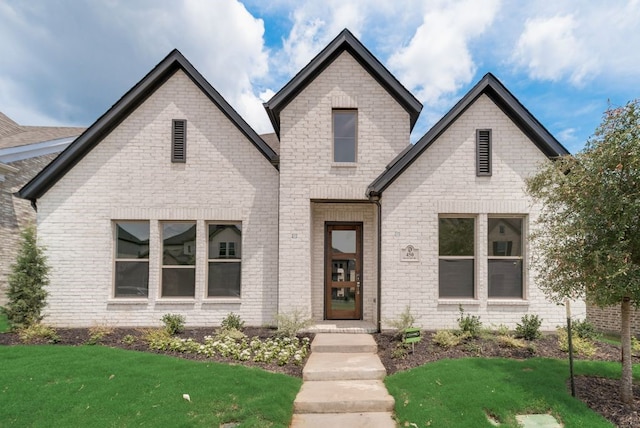 french country style house featuring brick siding and a front lawn