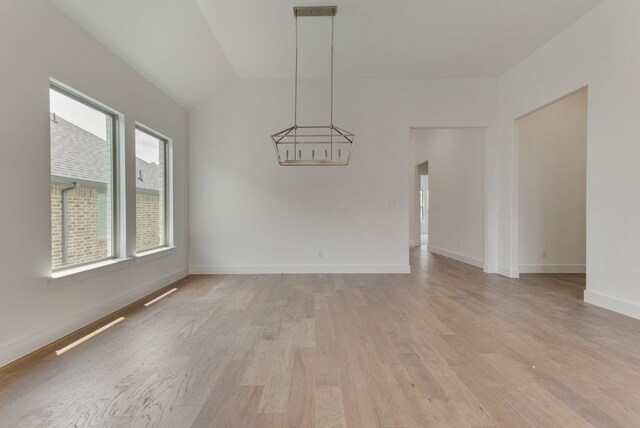 interior space with visible vents, baseboards, lofted ceiling, light wood-style flooring, and a chandelier