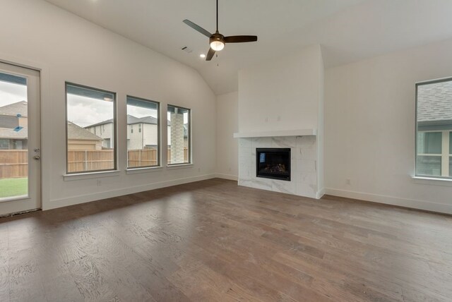 unfurnished living room with a healthy amount of sunlight, wood finished floors, a ceiling fan, and vaulted ceiling