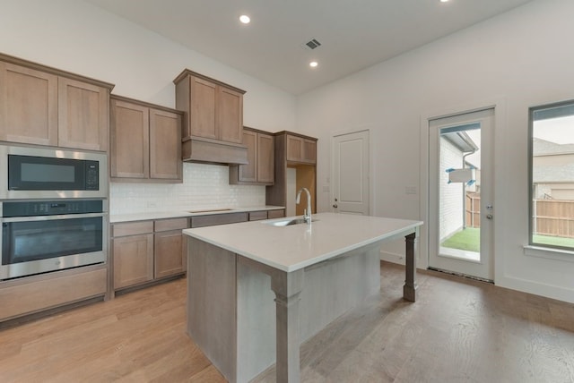 kitchen featuring visible vents, built in microwave, a sink, decorative backsplash, and oven