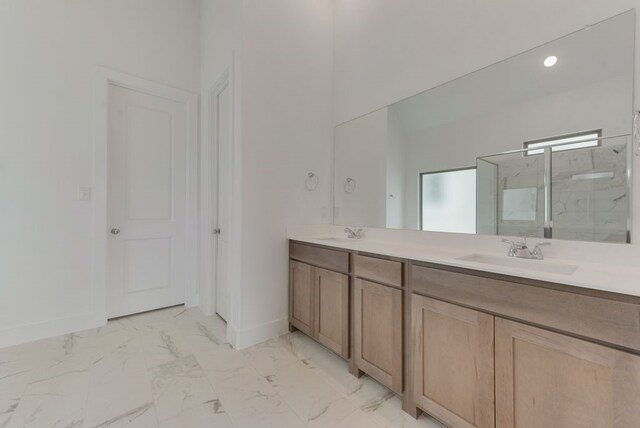 bathroom with double vanity, marble finish floor, a shower stall, and a sink