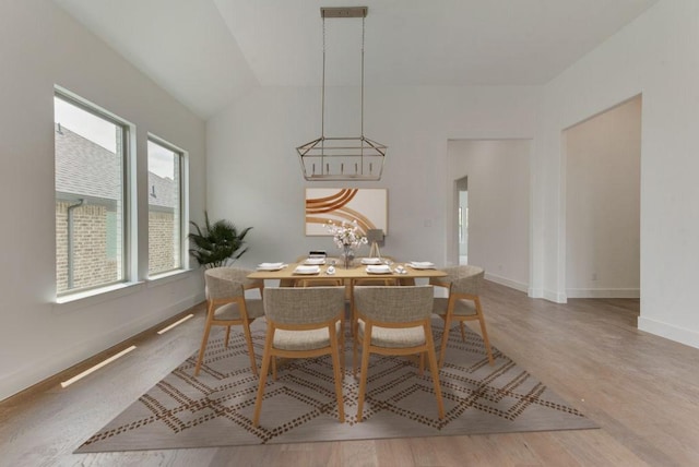 dining space featuring visible vents, baseboards, lofted ceiling, an inviting chandelier, and wood finished floors