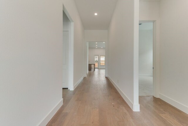 hall with recessed lighting, baseboards, and light wood finished floors