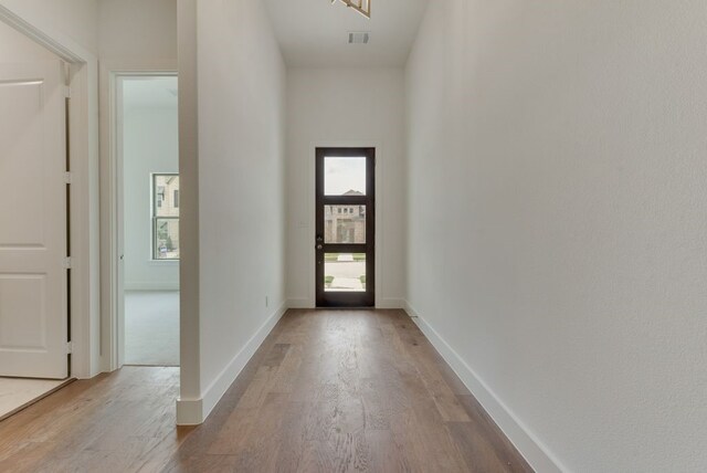 foyer entrance featuring visible vents, a high ceiling, baseboards, and wood finished floors