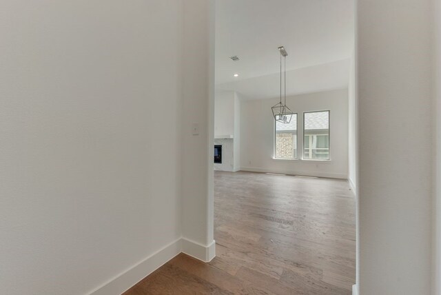 hallway featuring an inviting chandelier, wood finished floors, baseboards, and visible vents