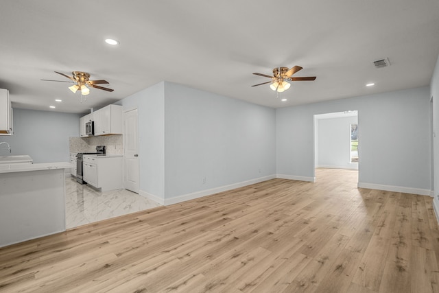 unfurnished living room featuring baseboards, ceiling fan, light wood-type flooring, recessed lighting, and a sink