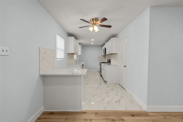 kitchen featuring baseboards, light countertops, decorative backsplash, appliances with stainless steel finishes, and a ceiling fan