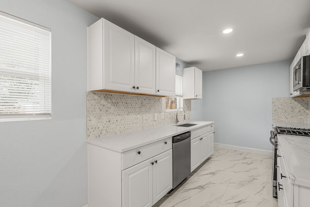 kitchen with baseboards, a sink, marble finish floor, appliances with stainless steel finishes, and tasteful backsplash