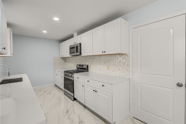 kitchen featuring a sink, white cabinets, appliances with stainless steel finishes, marble finish floor, and backsplash