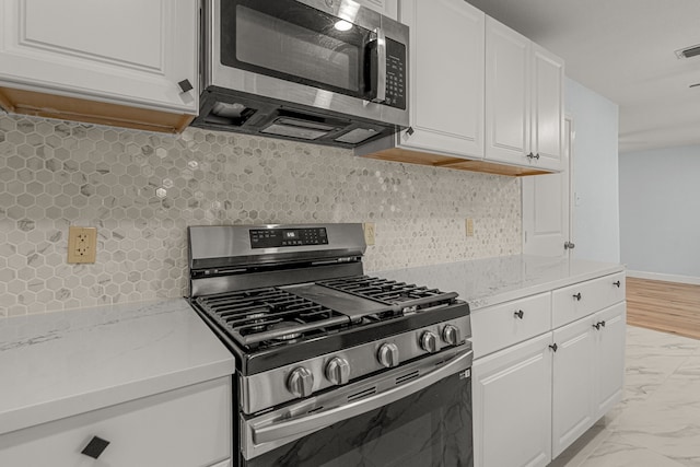 kitchen featuring decorative backsplash, marble finish floor, appliances with stainless steel finishes, and white cabinets