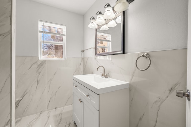 bathroom featuring plenty of natural light, tile walls, marble finish floor, and vanity