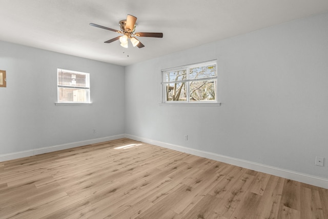 spare room with light wood finished floors, a healthy amount of sunlight, and baseboards