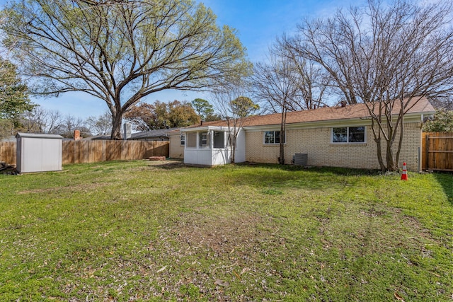 rear view of house with a lawn, a fenced backyard, a shed, an outdoor structure, and brick siding