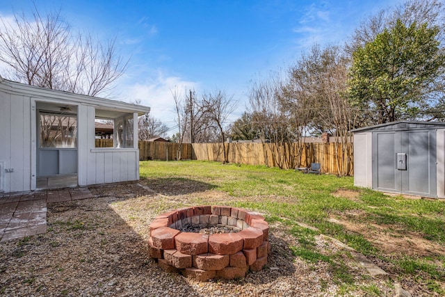 view of yard with an outbuilding, a fenced backyard, and an outdoor fire pit