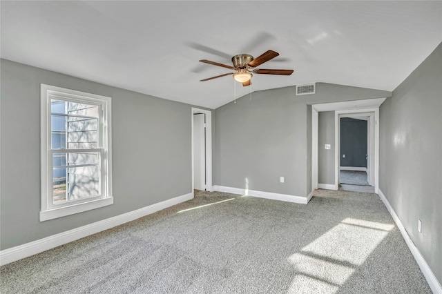 carpeted spare room featuring visible vents, lofted ceiling, baseboards, and a ceiling fan