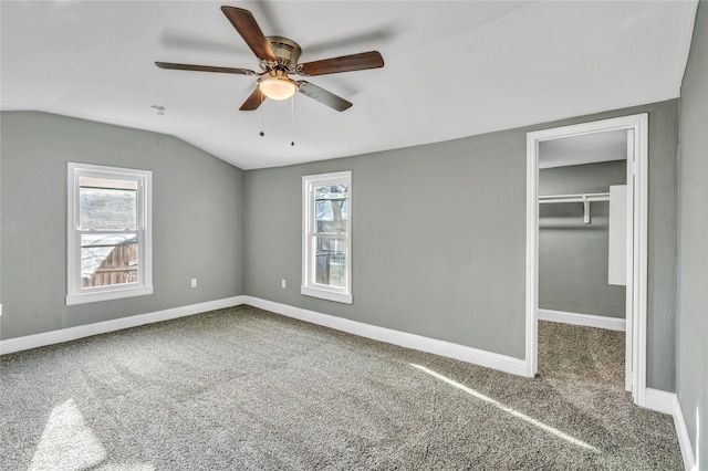 unfurnished bedroom featuring a spacious closet, carpet flooring, baseboards, and vaulted ceiling